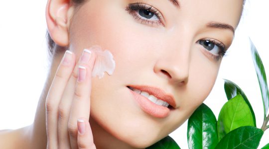 Woman applying moisturizer cream on face. Close-up fresh woman.